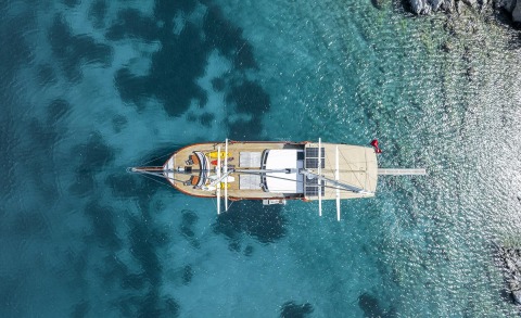 Overhead view of a sailing yacht on turquoise sea at sunset