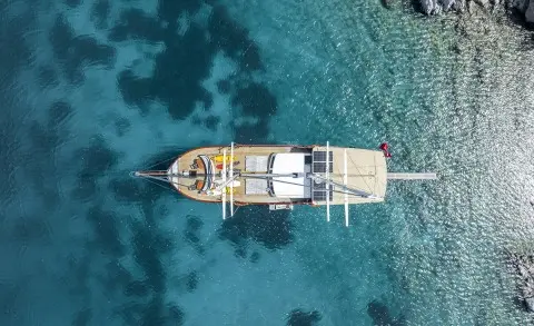 A white luxury gulet yacht anchored in clear turquoise water at sunset