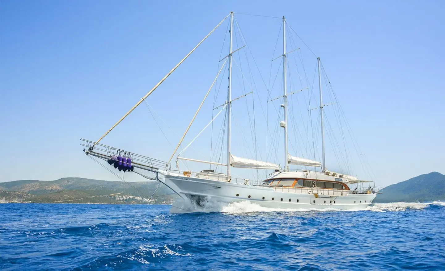 Bella Mare yacht anchored in turquoise sea with sails and clear blue sky