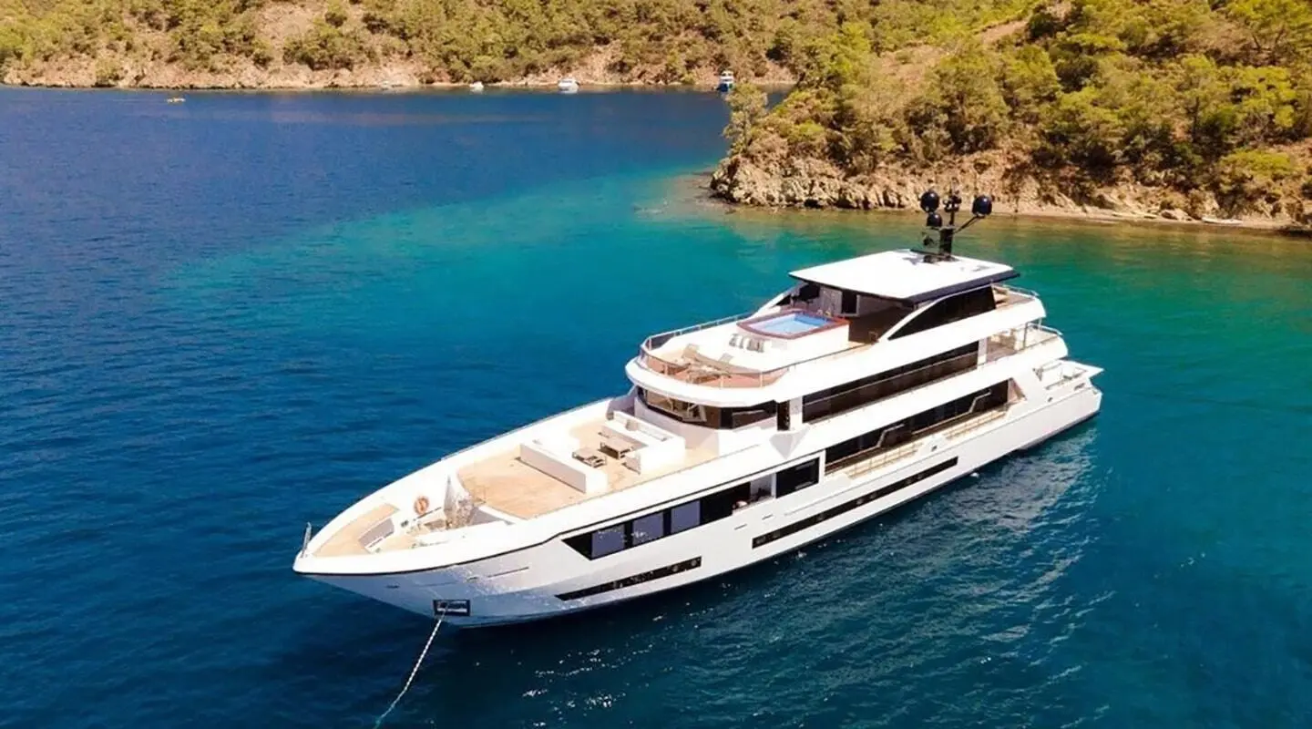 Ocean Breeze luxury motor yacht anchored near rocky coastline at sunset