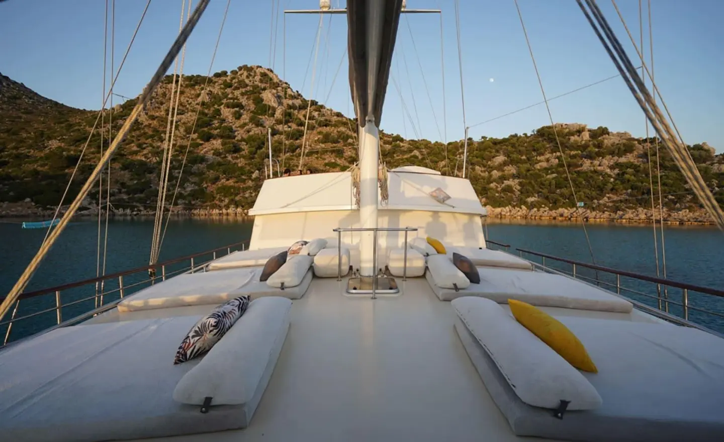 View from the yacht bow with sails and rigging set against sunset water