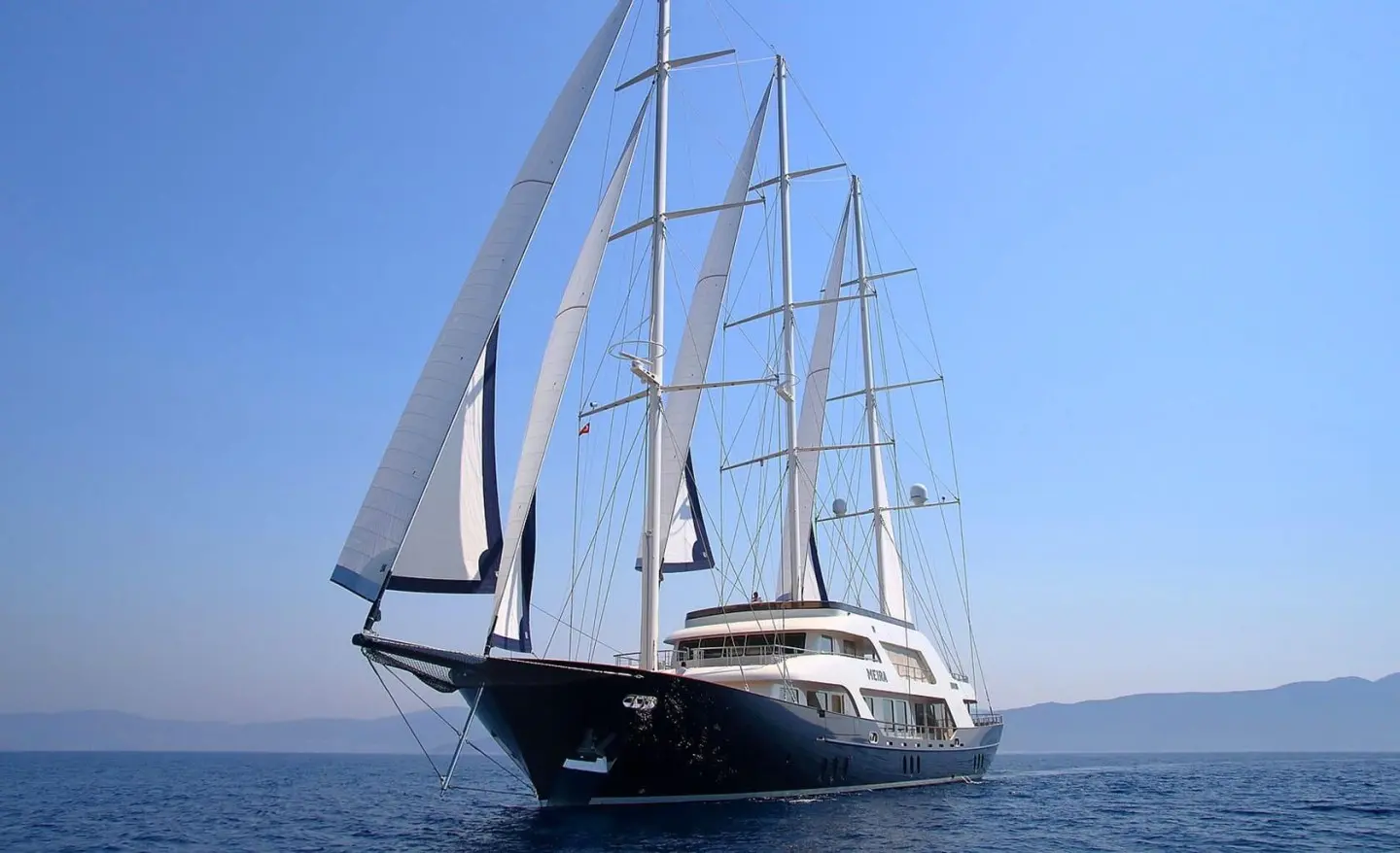 Meira luxury sailing yacht with dark hull and multiple tall masts on blue sea