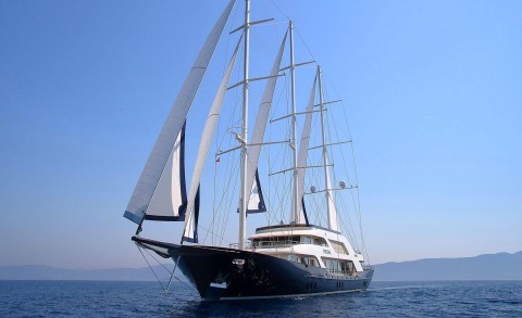 Meira yacht with bow visible, tall masts and sails, calm blue sea and clear sky