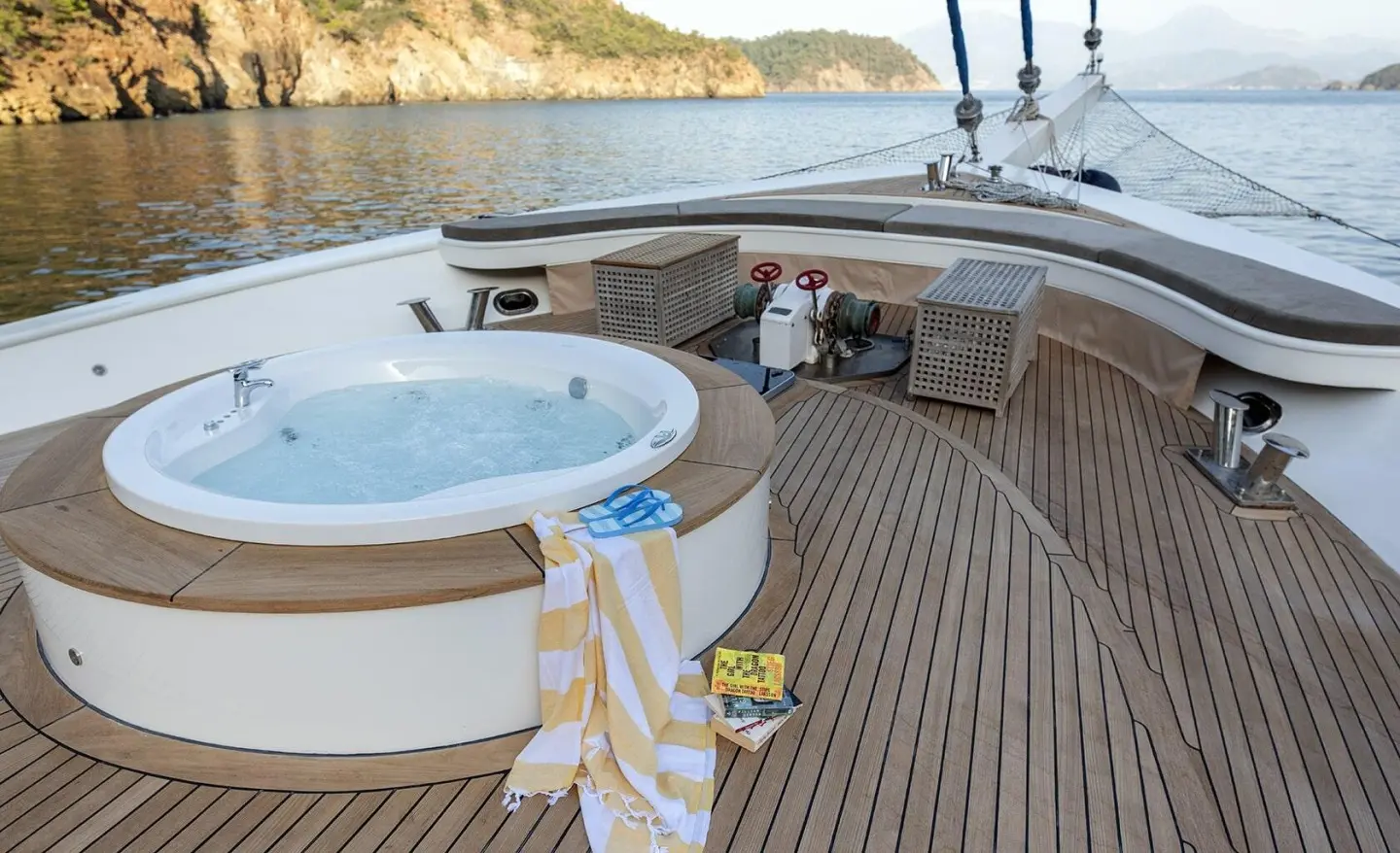 Kayhan Kaptan yachts’ aft deck with circular hot tub and teak flooring, sea backdrop