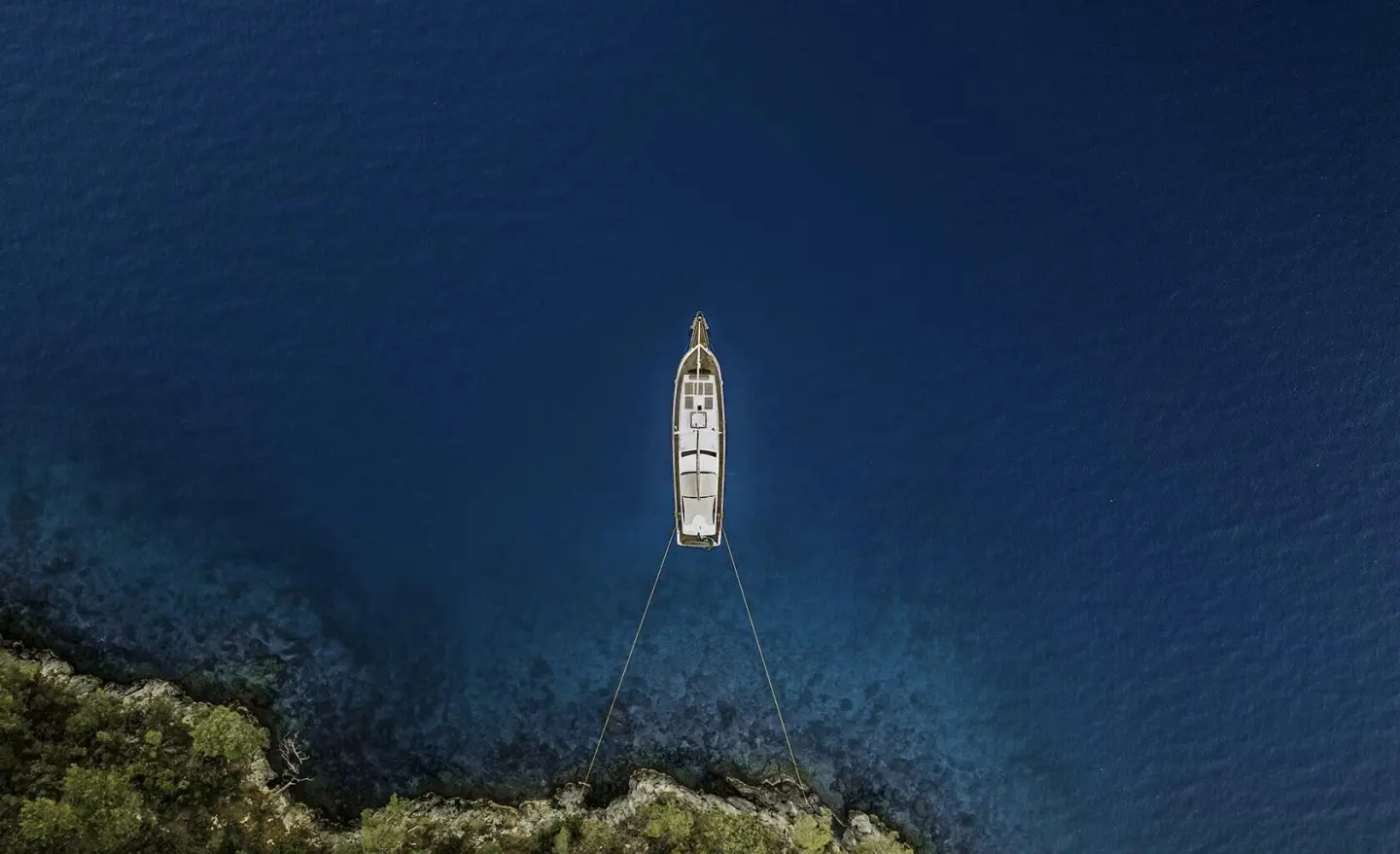 A luxury gulet yacht anchored in calm blue water at sunset.