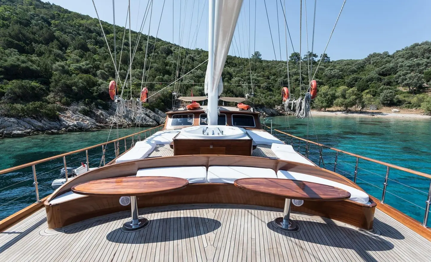 Grace 1 yacht bow deck with wooden railing and white sails visible