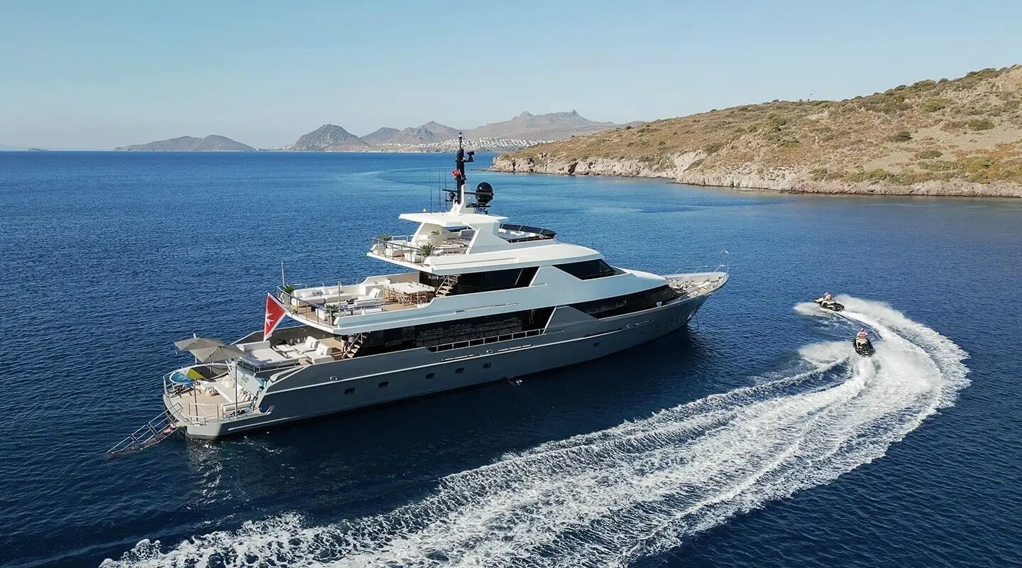 Illusion II yacht cruising on blue water with wake near coastline
