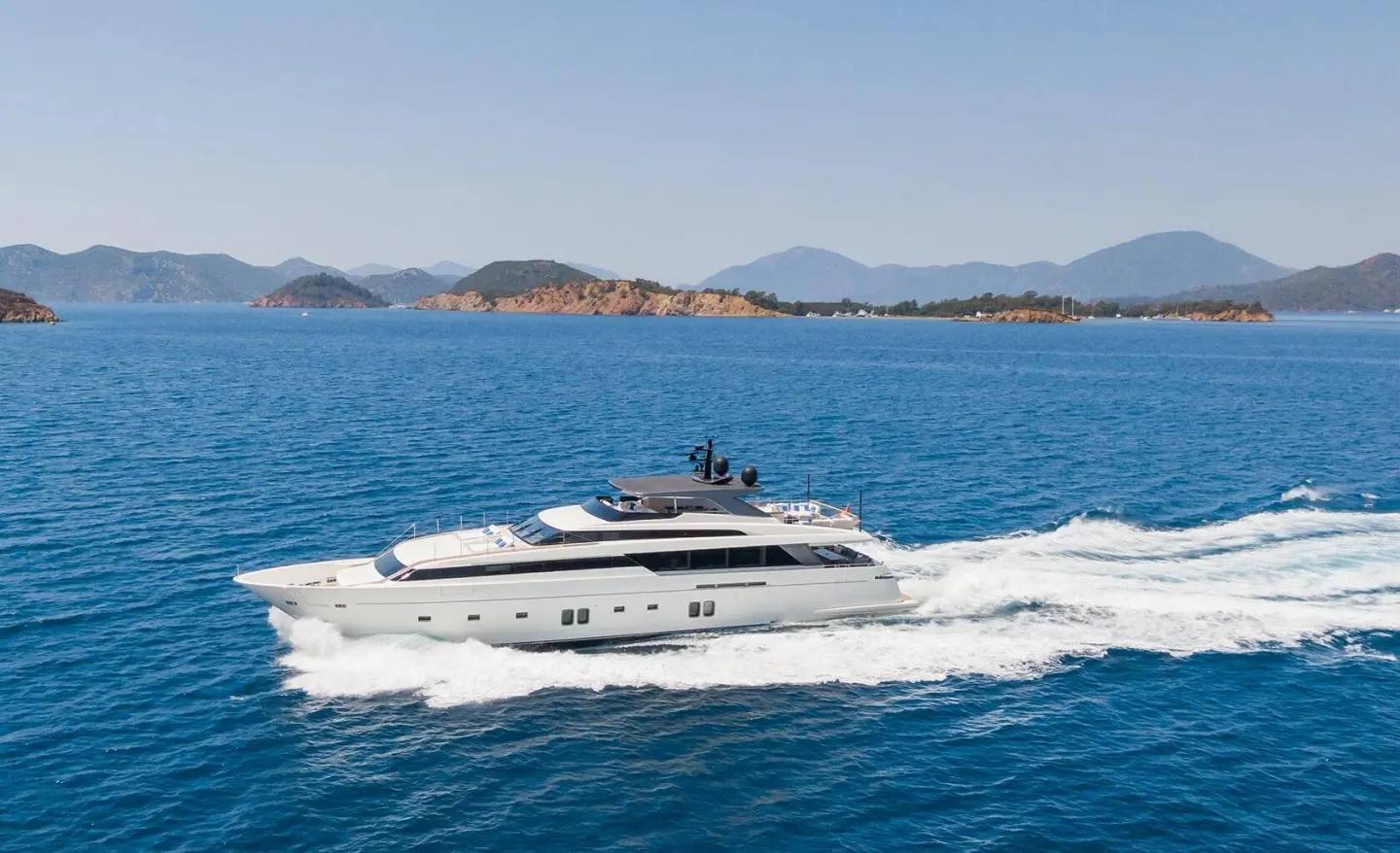 Morning Star luxury yacht cruising on blue sea with wake and distant islands