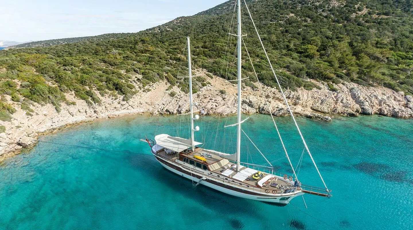 Estrella De Mar sailing yacht anchored near rocky turquoise cove with clear waters