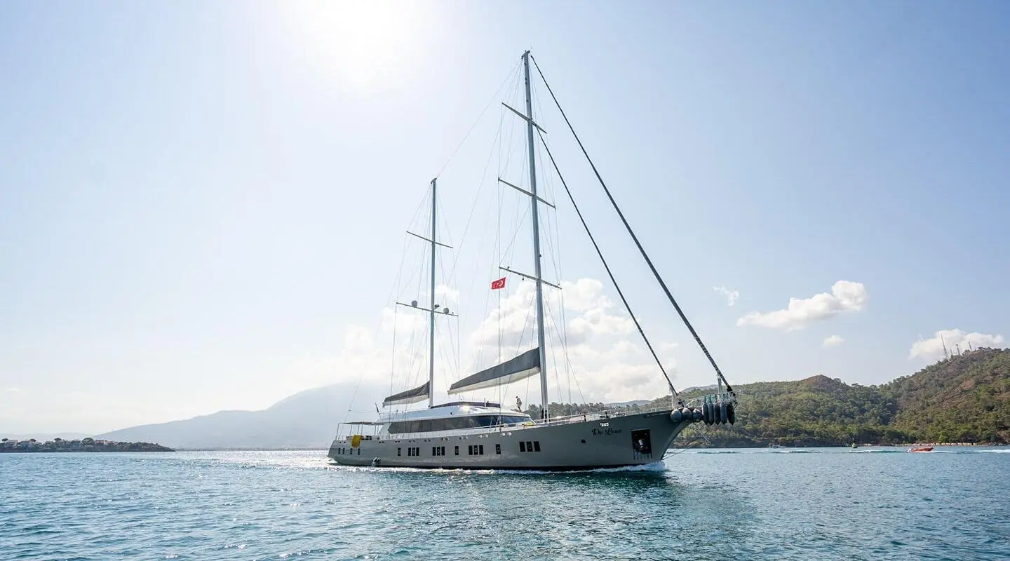 Sailing yacht De Love anchored in calm blue water under clear sky