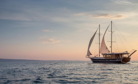 Sailing gulet Altair on the sea at sunset, viewed from the side with sails and masts
