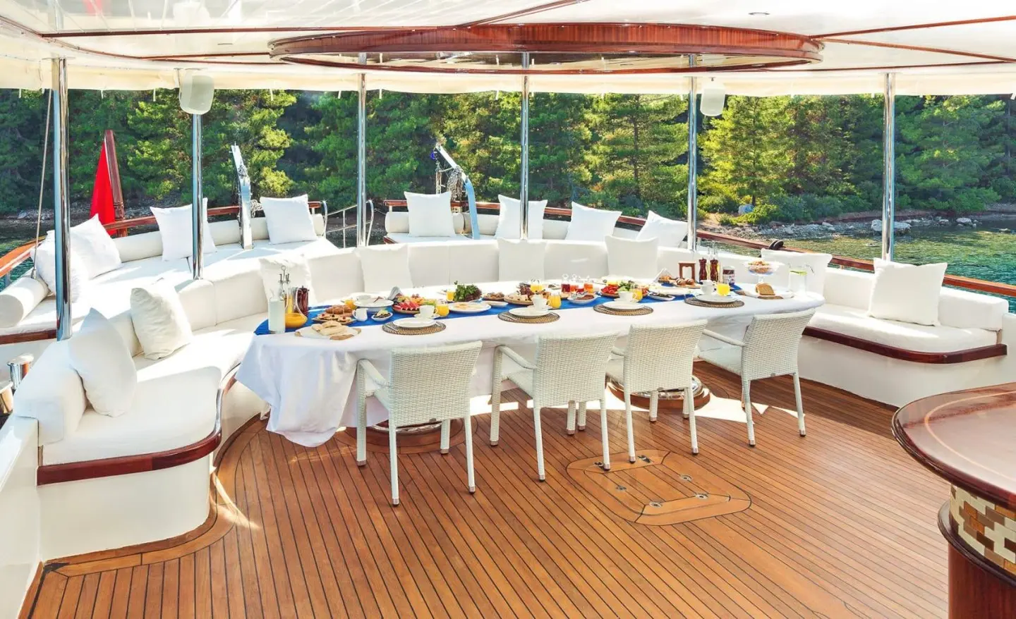 Halcon Del Mar yacht on a sunny deck with a long banquet table set for dining