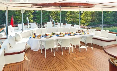 Halcon Del Mar yacht on a sunny deck with a long banquet table set for dining