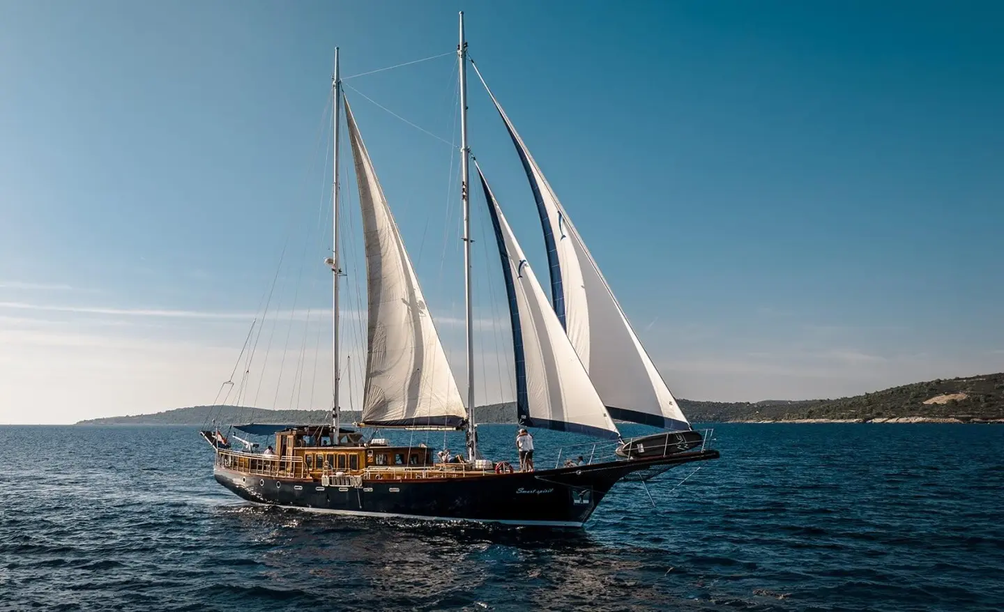 Elegant sailing yacht with white sails gleaming under a blue sky on calm sea