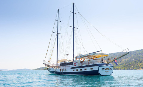 Sailing gulet yacht anchored in calm turquoise sea with two masts