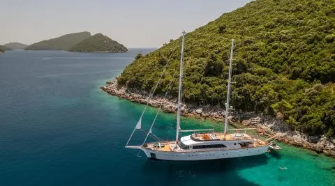 Gulet Love Story anchored near a rocky hillside with clear blue water
