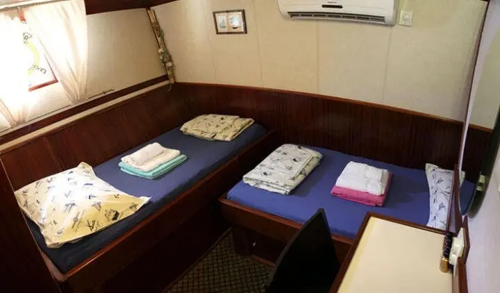 Twin cabin beds with blue towels and small bedside table in yacht Tajna Mora cabin