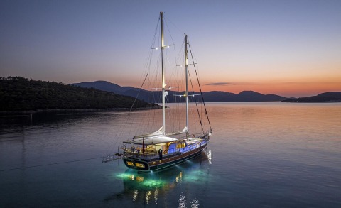 Two-masted luxury sailing yacht anchored on calm water at sunset