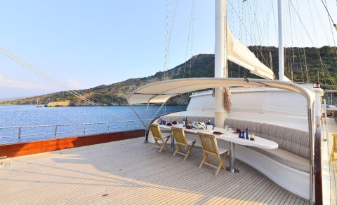 Berrak Su yacht deck with dining table and seating under awning overlooking blue sea