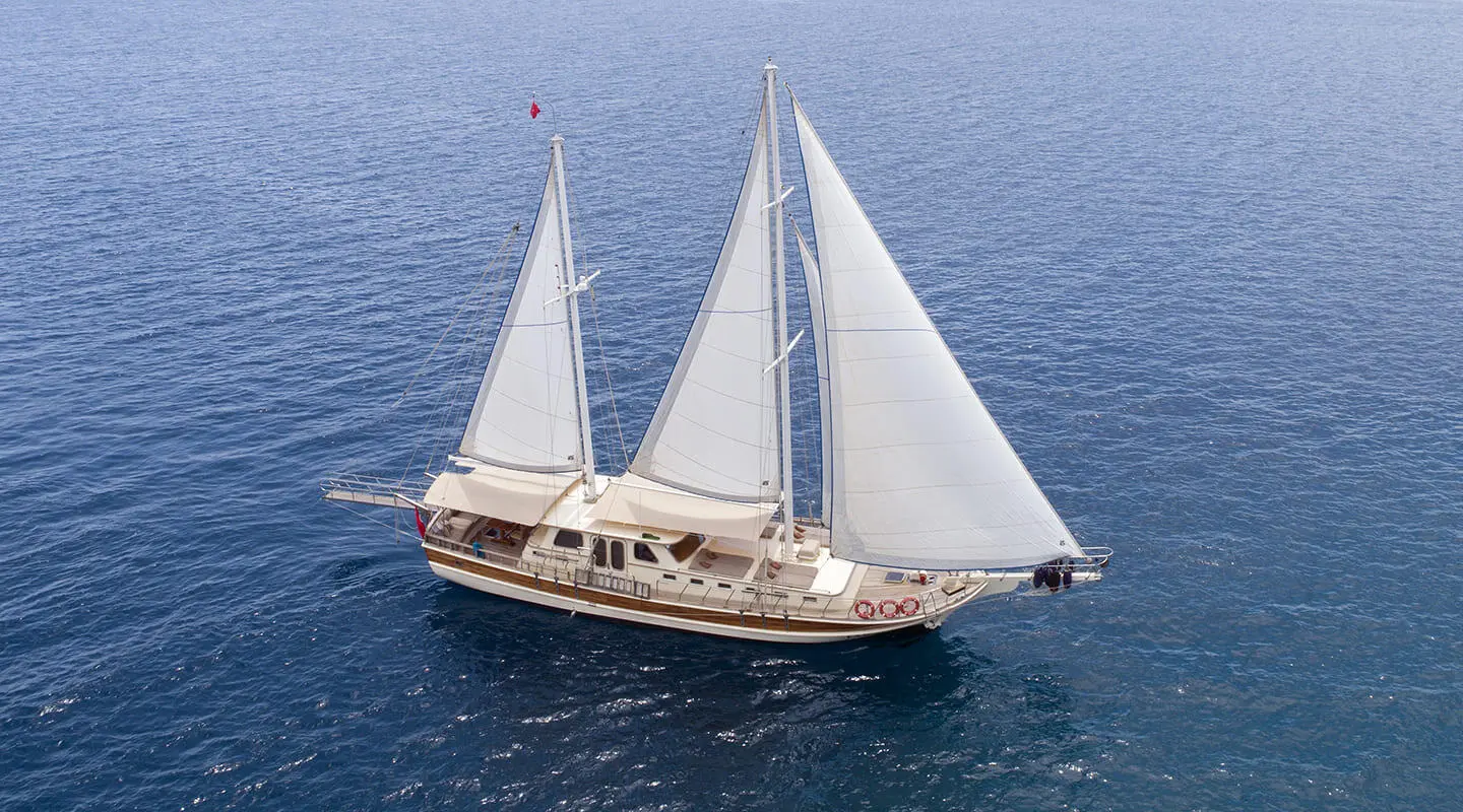 Faralya luxury gulet sailing on calm sea at sunset with tall masts