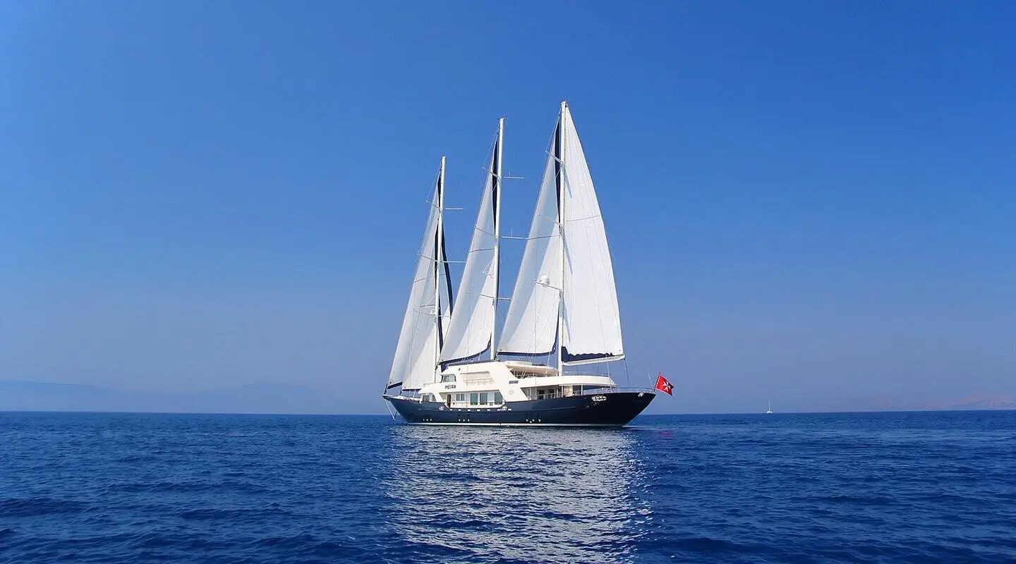 Three-masted sailing yacht Meira on blue sea with sails up