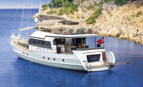 Maske 5 yacht anchored near rocky coastline with outdoor deck and Turkish flag