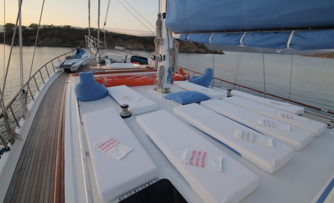 Sunset view from Ece Berrak gulet deck with white cushions and blue pillows along the water