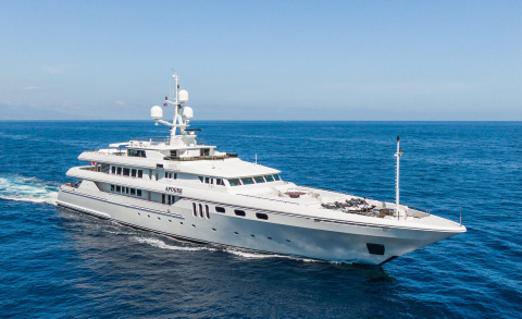 White motor yacht Apogee cruising in blue sea, upper deck visible with windows and deck details
