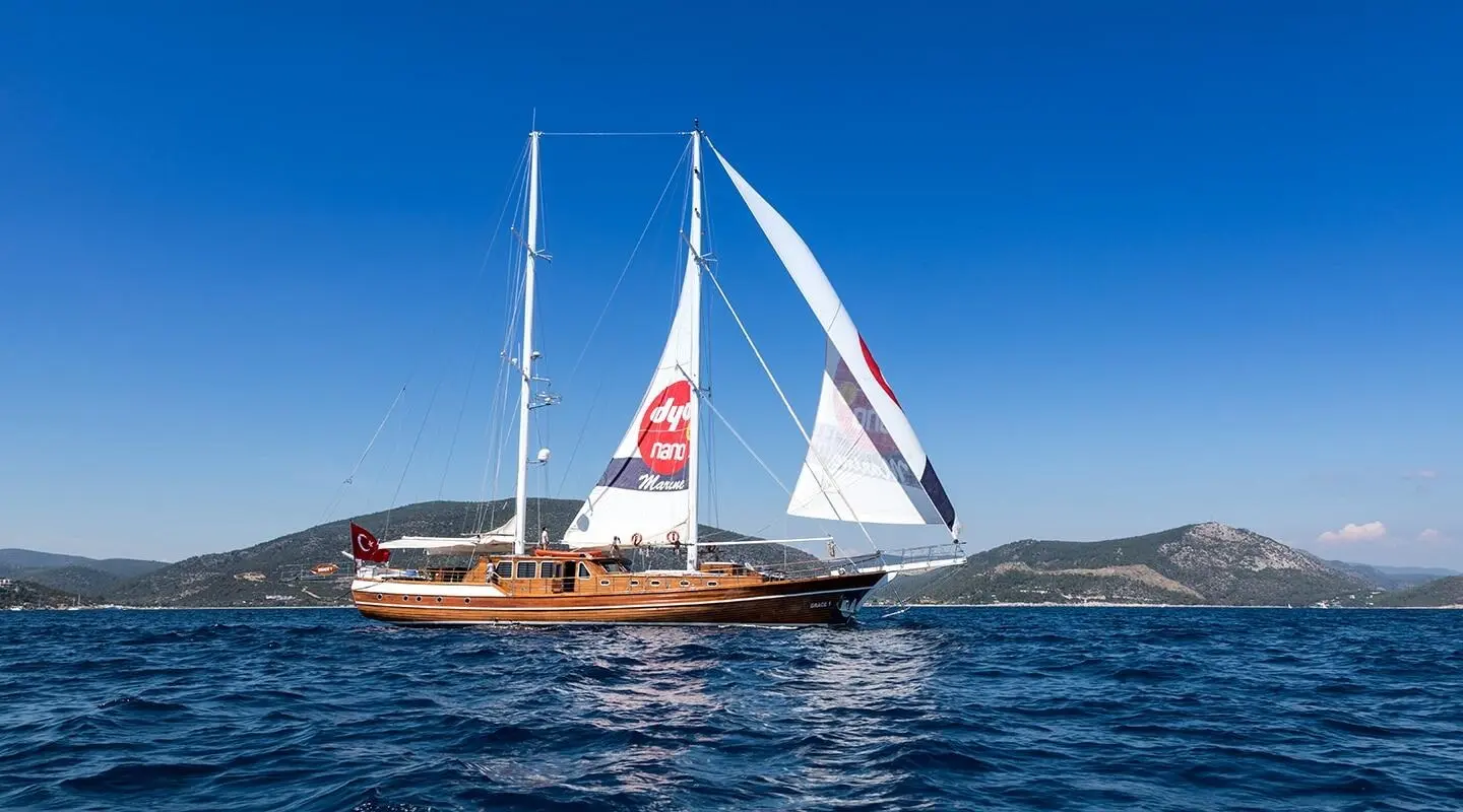 Grace 1 yacht with sails unfurled on calm blue sea at sunset harbor