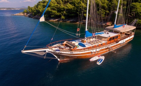 Luxurious wooden gulet Malena with deck seating and masts on calm sea
