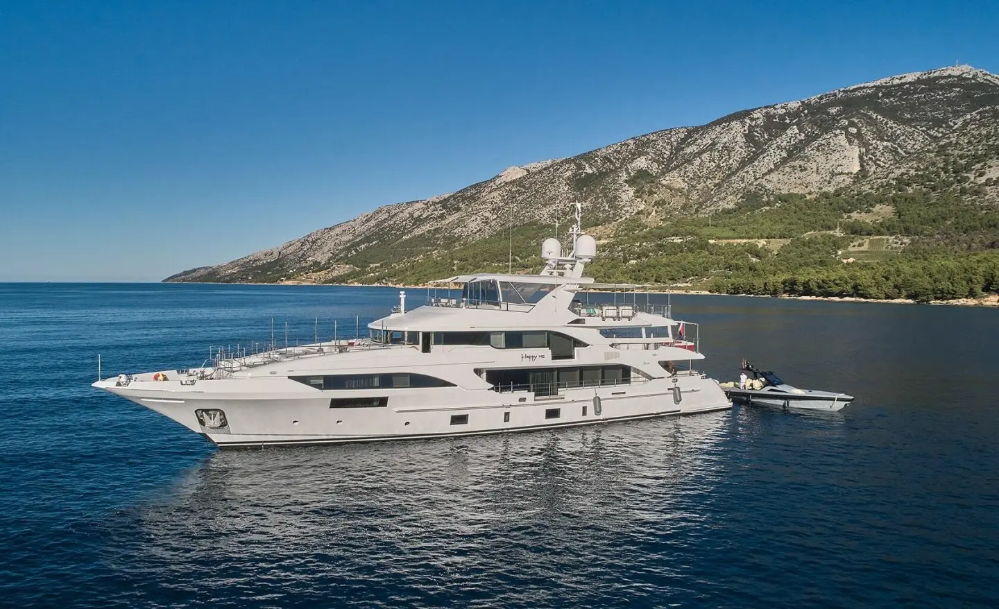 Side view of a luxury yacht named Happy Me docked in calm blue waters