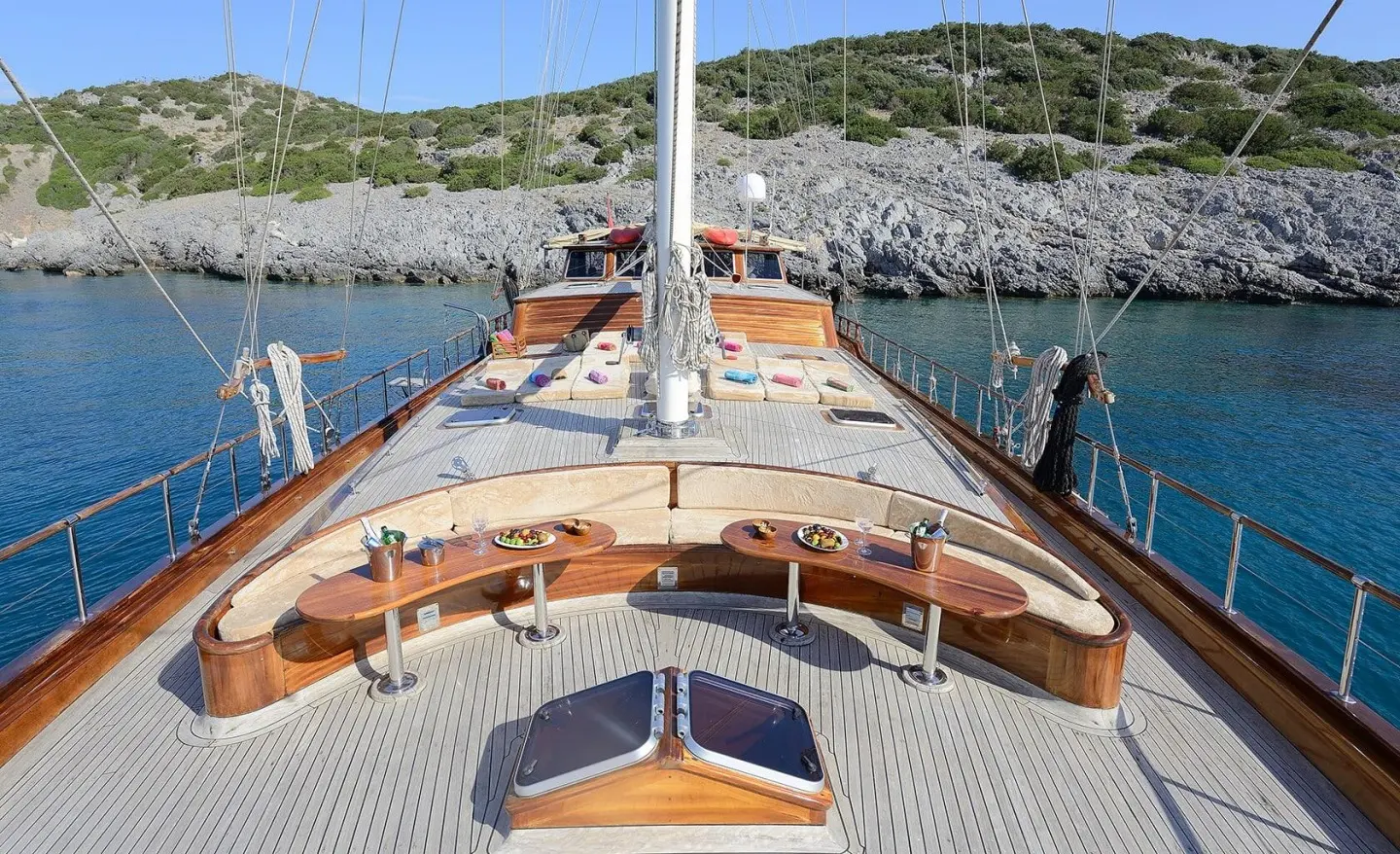 View from the yacht deck showing a central mast, seating area, and water on both sides
