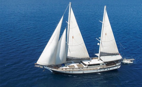 White luxury sailing yacht with multiple sails on open blue sea