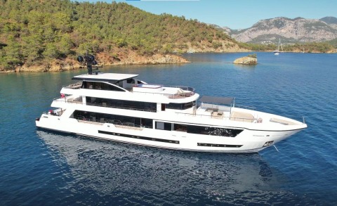 Ocean Breeze luxury yacht anchored in turquoise coastal waters with forested shorelines