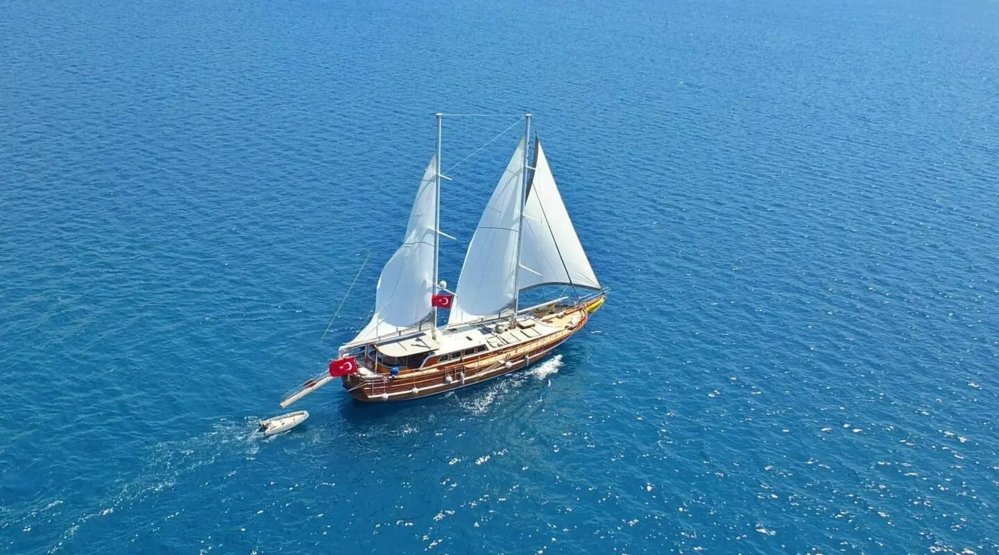 Aerial view of a luxury gulet sailing on calm blue sea at sunset