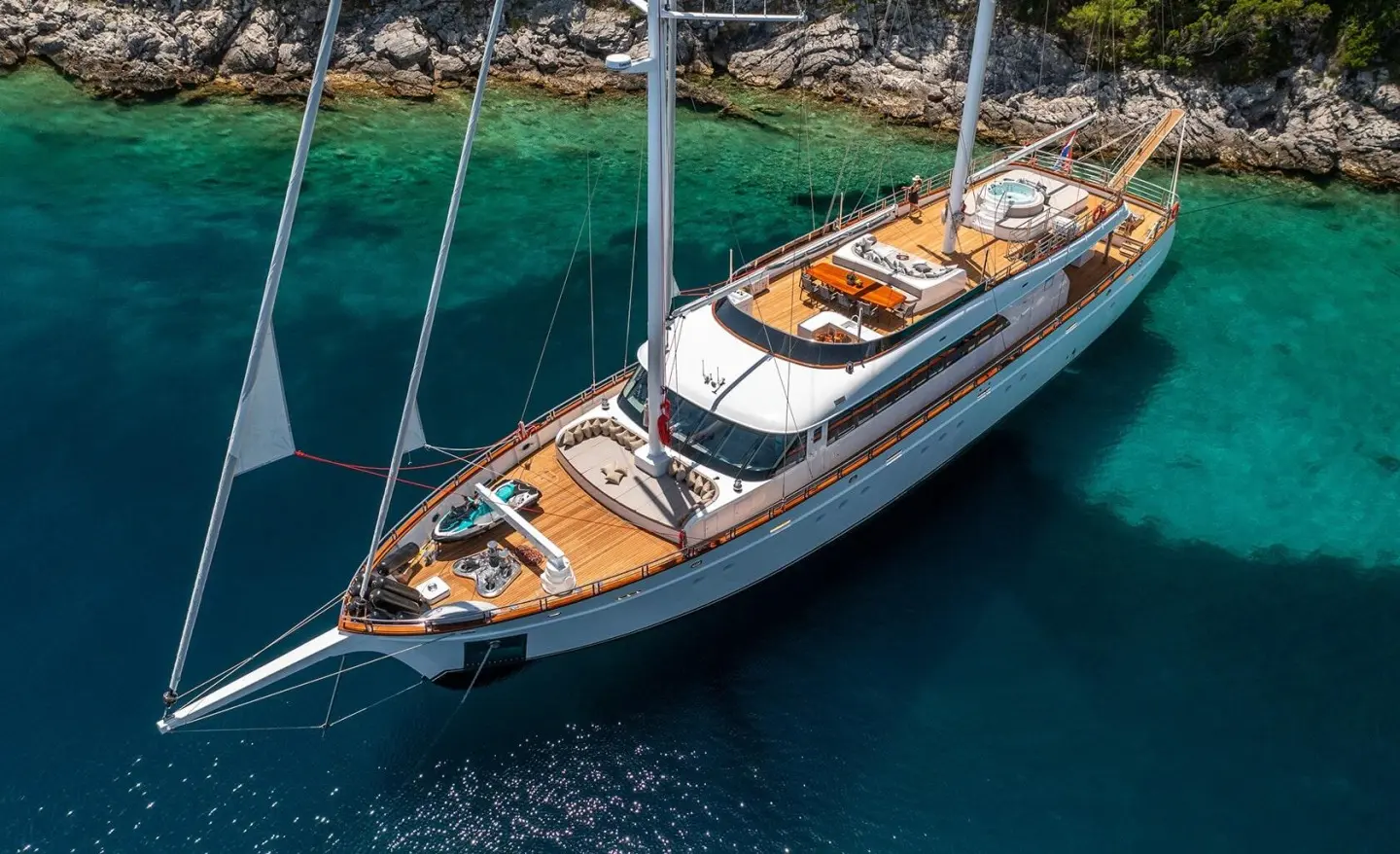 A white luxury sailing yacht named Love Story anchored in turquoise water at sunset