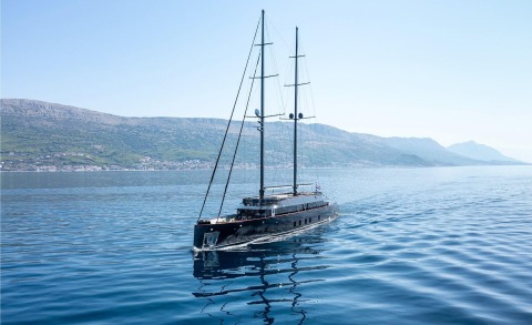 Blue sea with a sailing motor yacht Scorpios near the coast and hills in the background