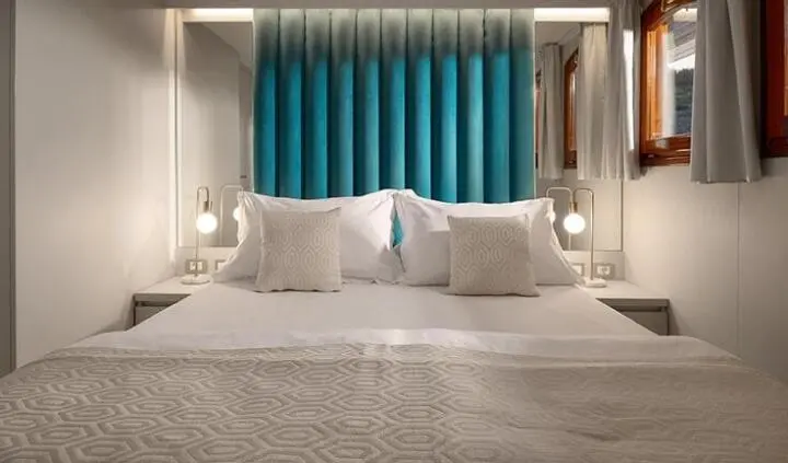 Master cabin with king bed and plush white bedding on Bellezza yacht