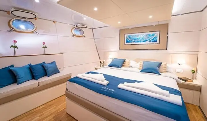 Master cabin with king bed, blue and white bedding, ensuite visible, wood floor