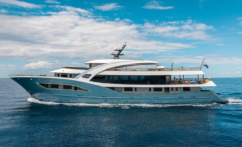 Bella luxury blue motor yacht cruising calm sea with open sun deck and white superstructure
