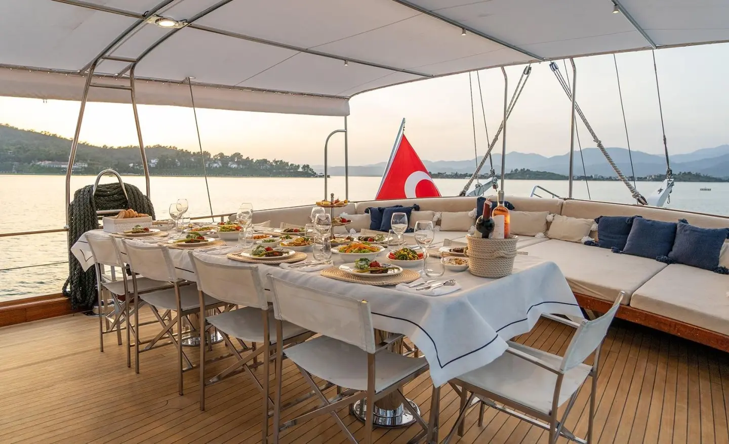 Elegant yacht dining setup on deck at sunset with white tablecloths