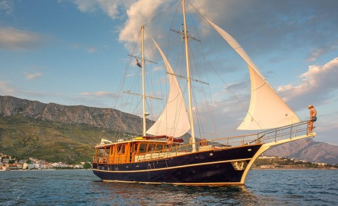 Altair gulet sailing yacht with dark hull and large white sails on calm sea