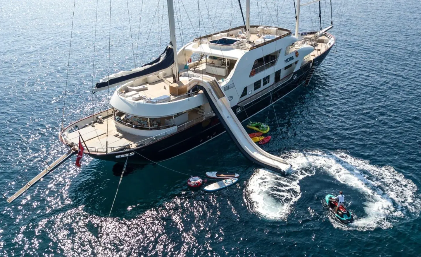 Meira luxury yacht anchored beside clear blue water, with deck seating and sunshade