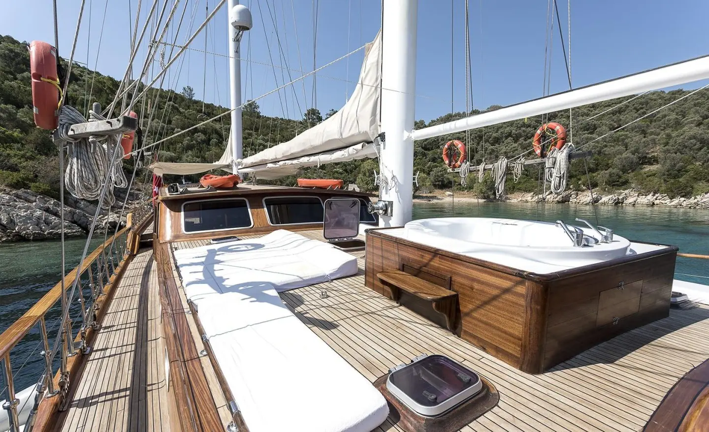 Grace 1 gulet deck with sunbeds and wooden railings under sails