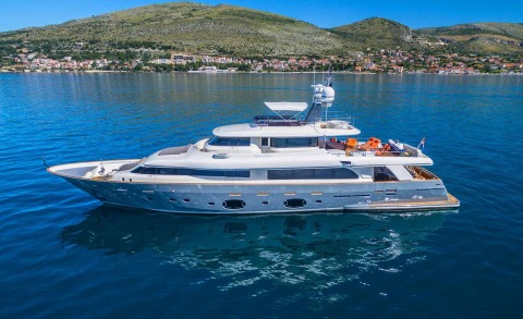 Seventh Sense luxury motor yacht anchored offshore with coastline hills in the background