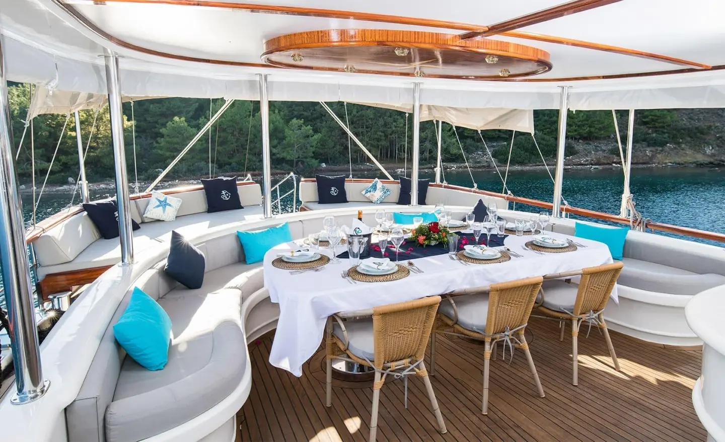 Aft deck of gulet Vista Mare with table set for dining and blue cushions
