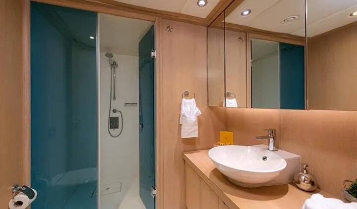 Guest cabin ensuite on Grace yacht with shower, wooden walls, and sink