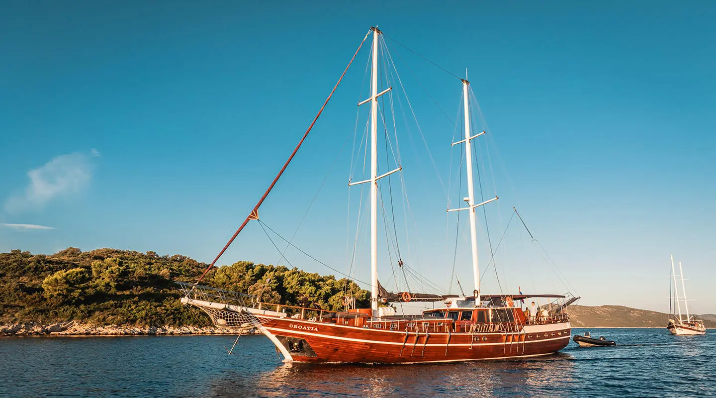 Croatia luxury sailing yacht anchored in turquoise waters near a tree-lined coastline
