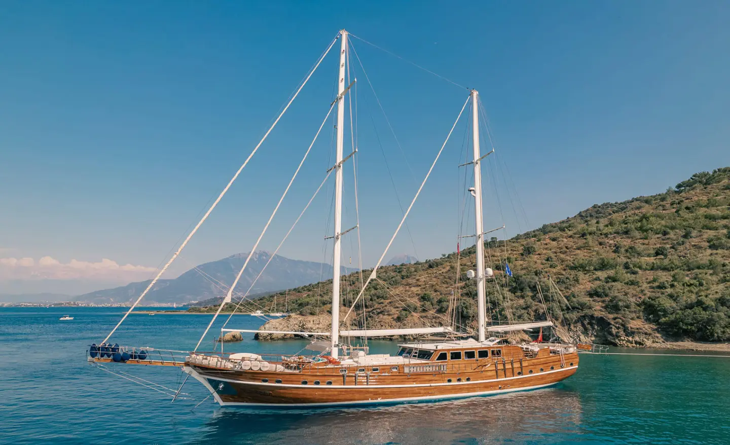 Lycian Queen luxury gulet anchored near rocky coastline at sunset, wooden hull