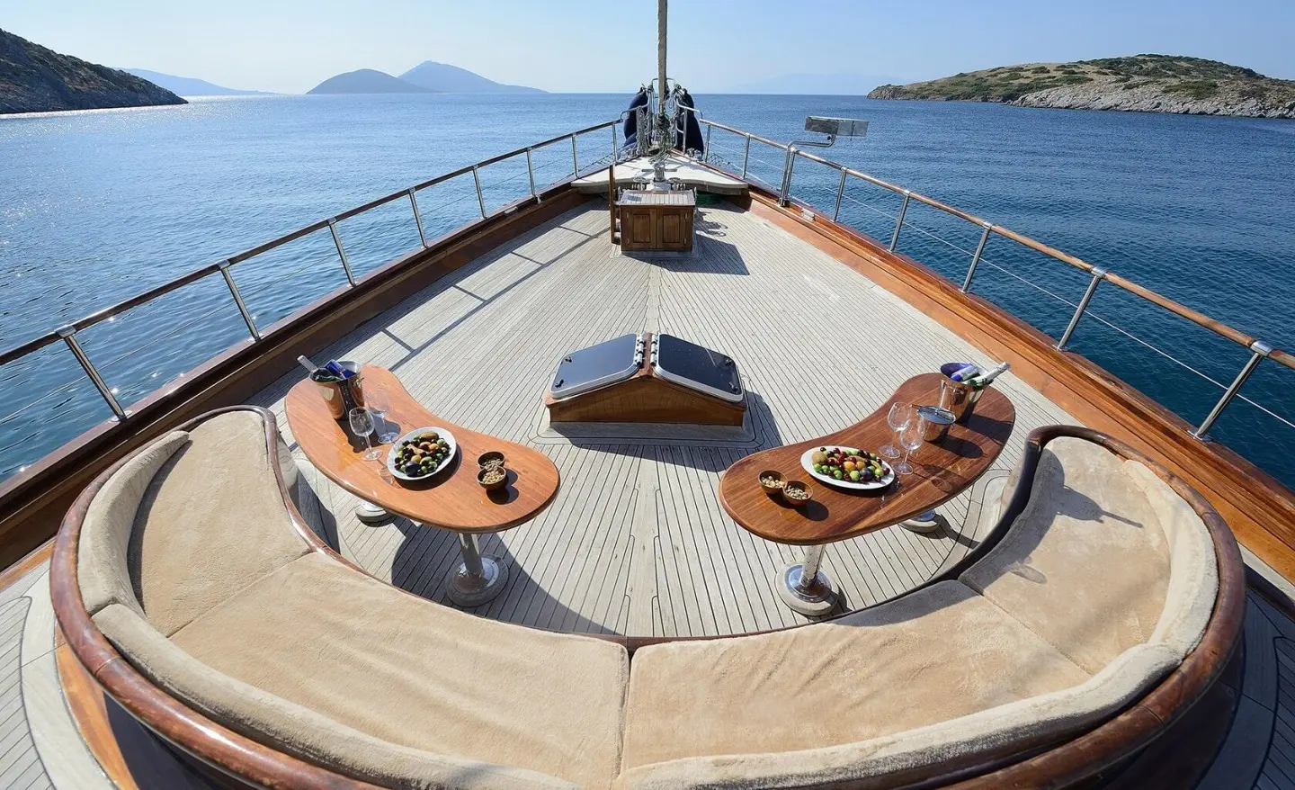 Zephyria II yacht bow deck with curved seating and wooden tables overlooking blue sea